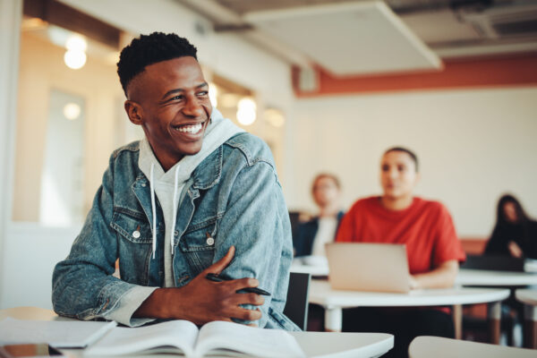 Smiling Male Student Sitting In University Classroom